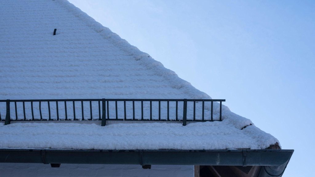 a house with a metal roof and a snow retention system is covered with snow