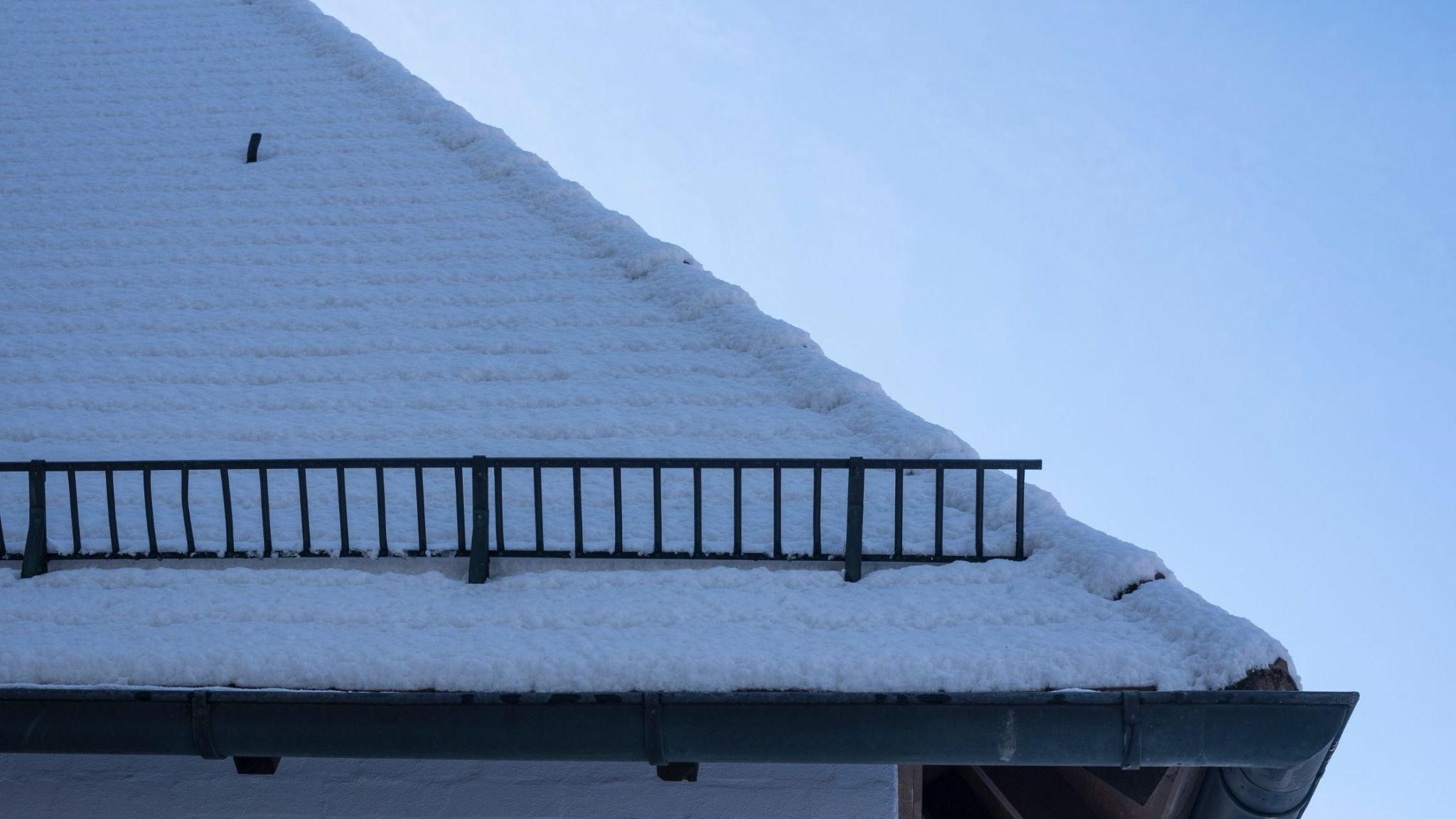 a house with a metal roof and a snow retention system is covered with snow